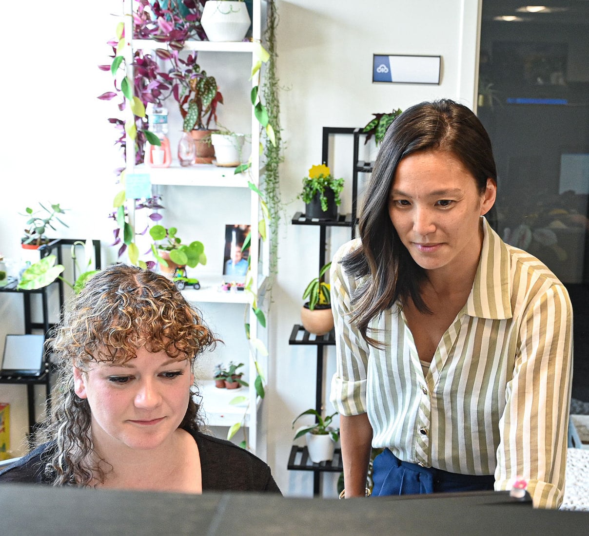 Two women focused on a computer screen in an office setting.