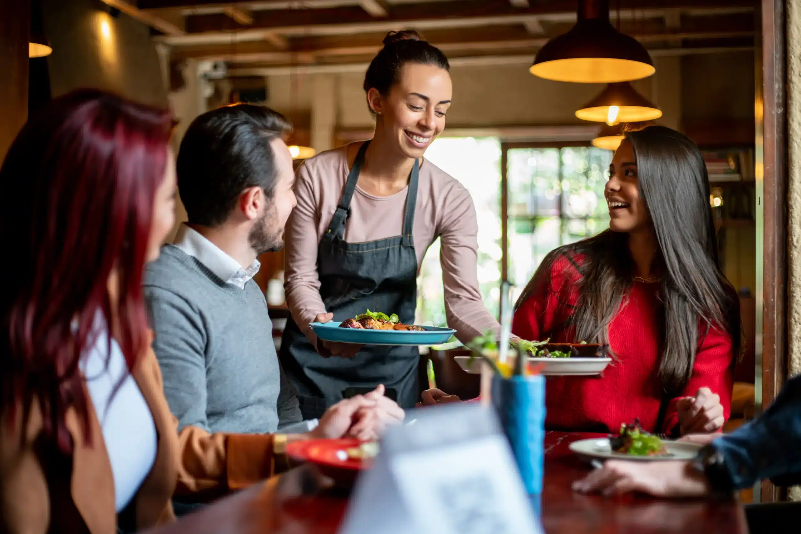 A server delivers food to guests seated at a table