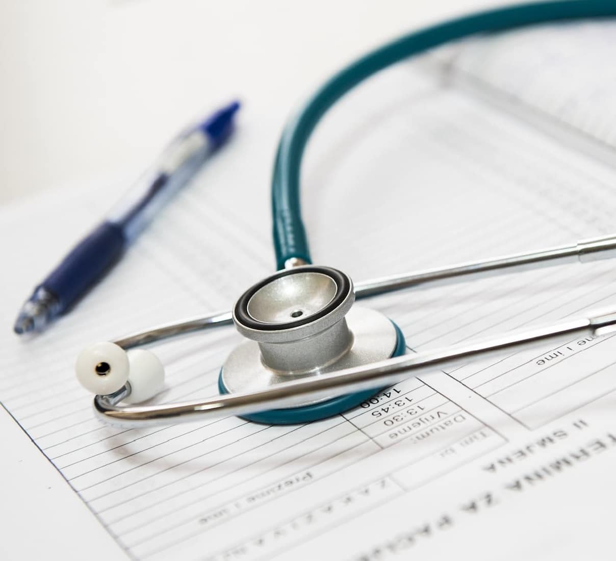 A close-up photo of a stethoscope and pen laid over medical paperwork.