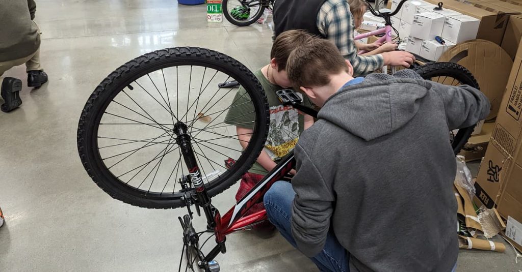 An OpenEye employee helps a student assemble their own bike at the 2023 Bike Build