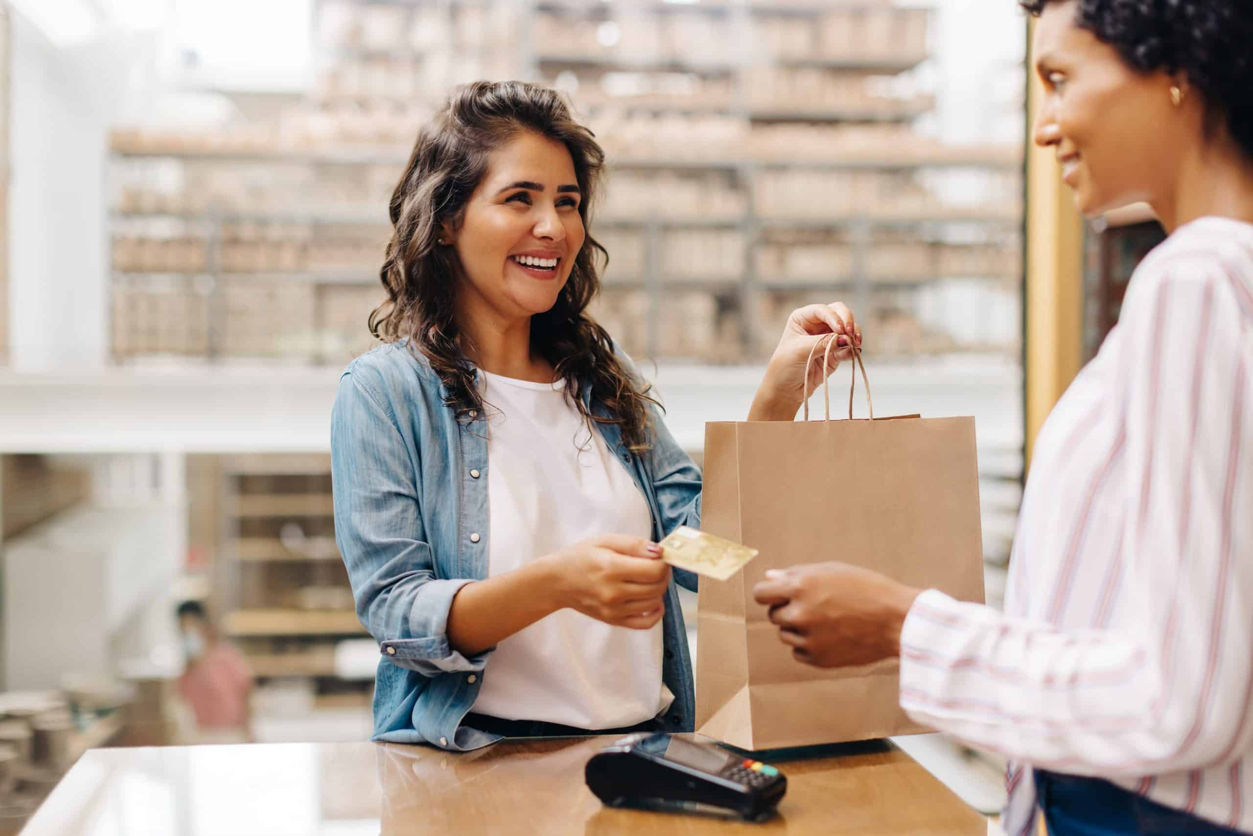 A woman giving her credit card to a cashier in a retail store.