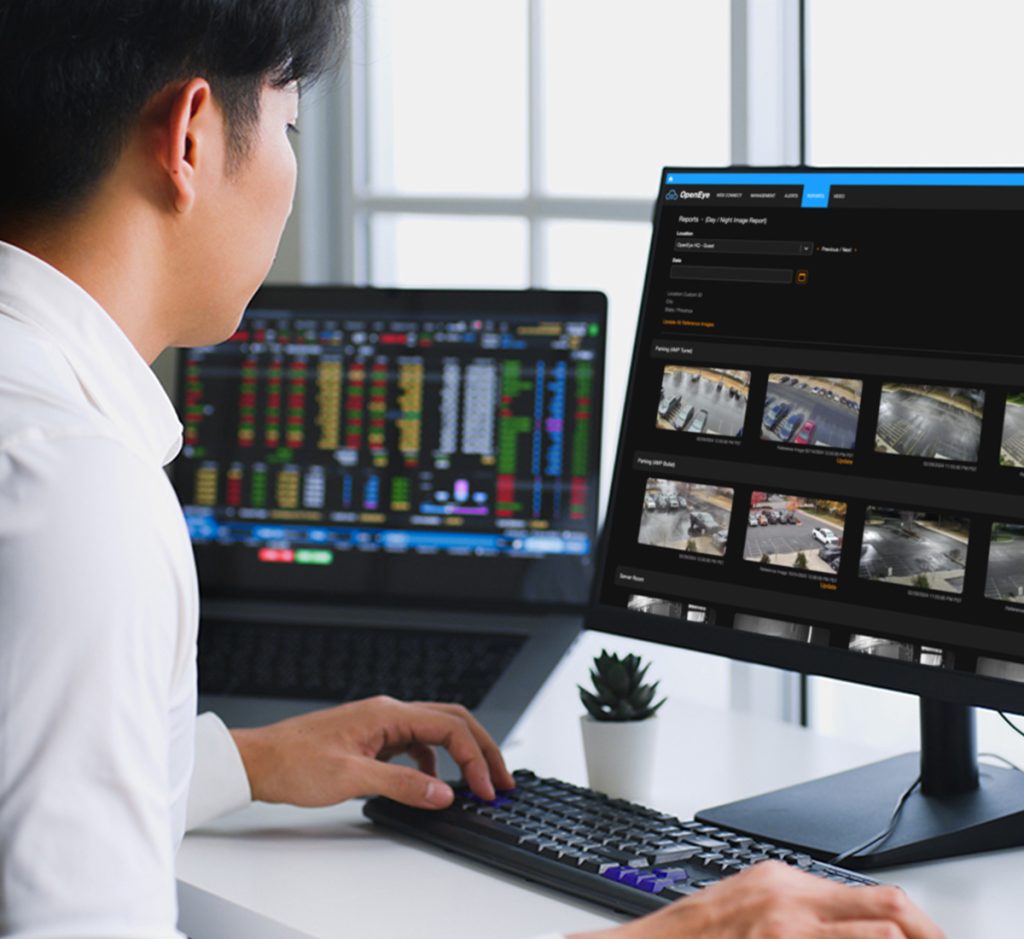 A man sits at a desk looking at a computer screen displaying OpenEye Web Services.
