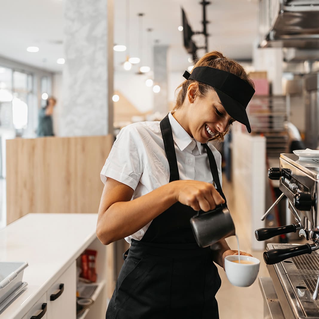 A barista pours milk into a cappuccino