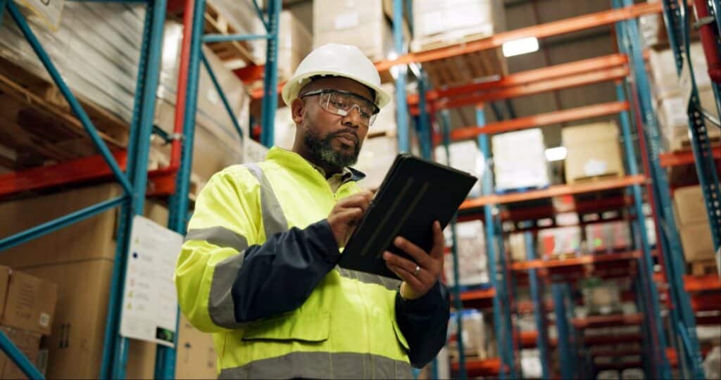 A person in a safety vest and hardhat holding a tablet