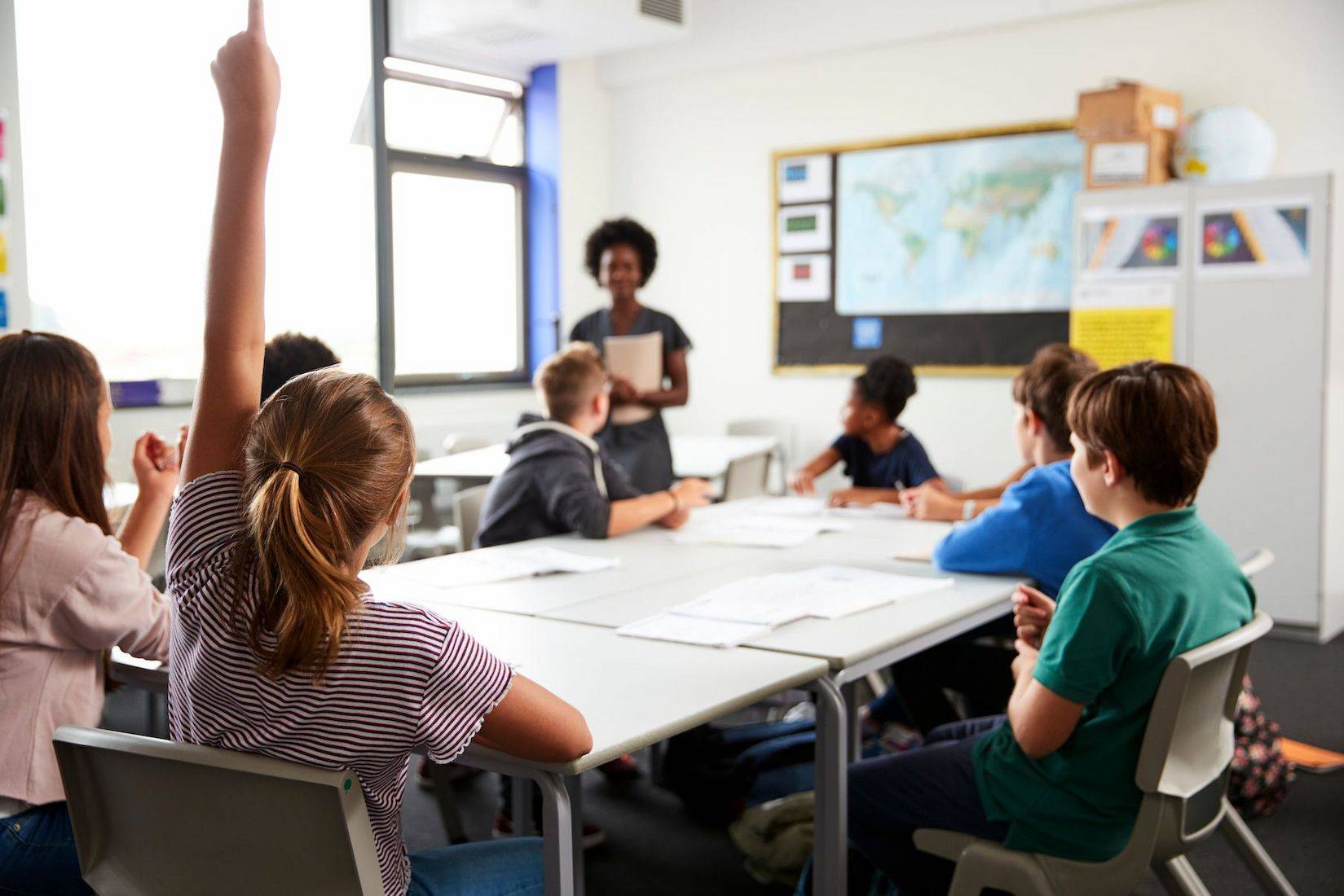 A group of children attentively sitting at desks in a bright classroom setting