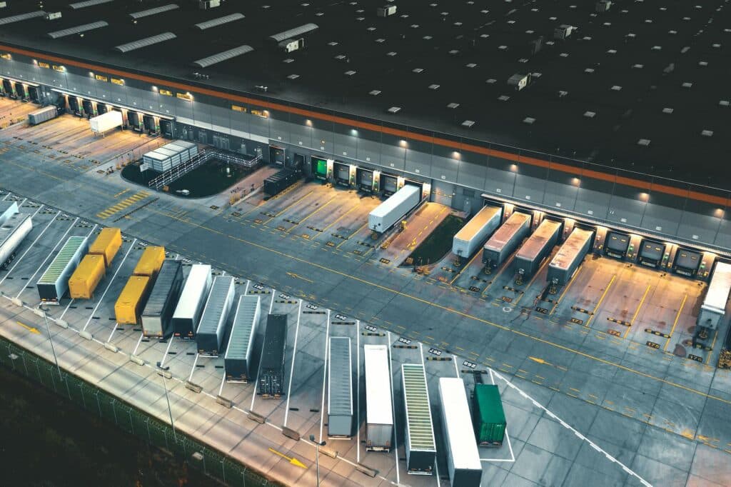Aerial view of a large warehouse surrounded by parked trucks.