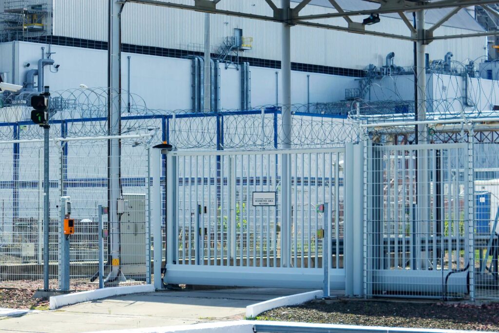 View of an industrial area surrounded by a large fence and gate.