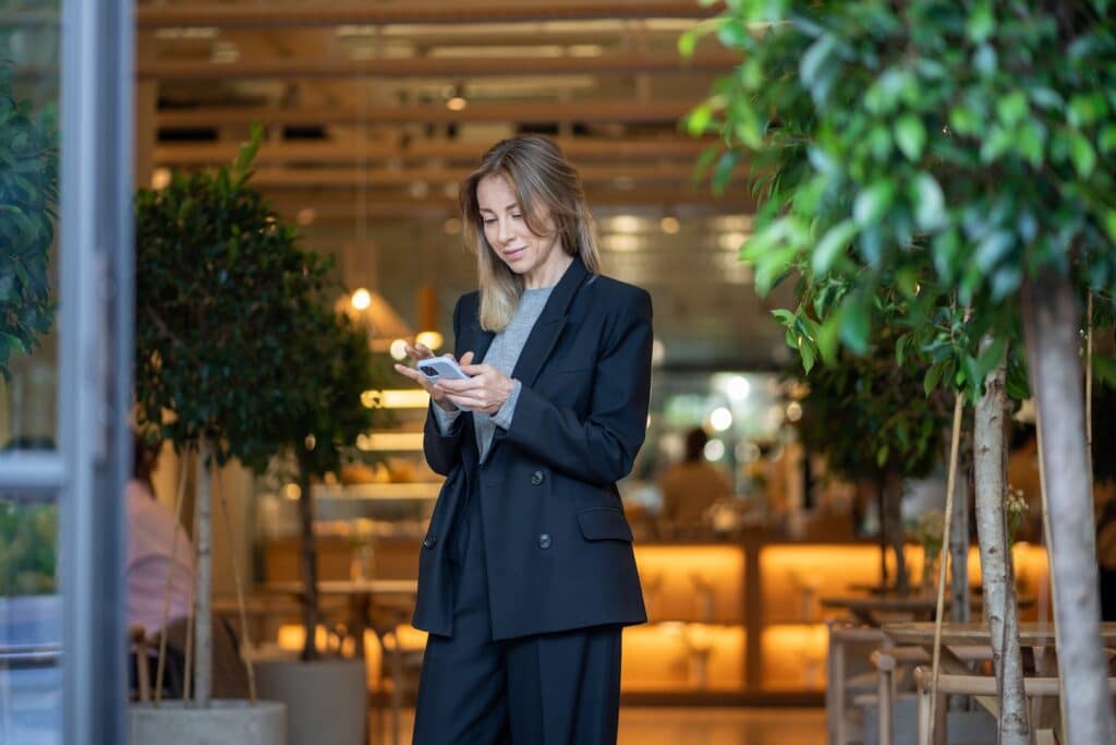 A woman stands looking at her phone&nbsp;