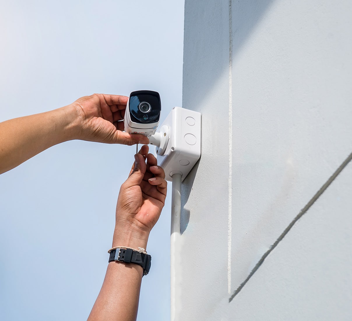 A person positions a video surveillance camera against an exterior wall