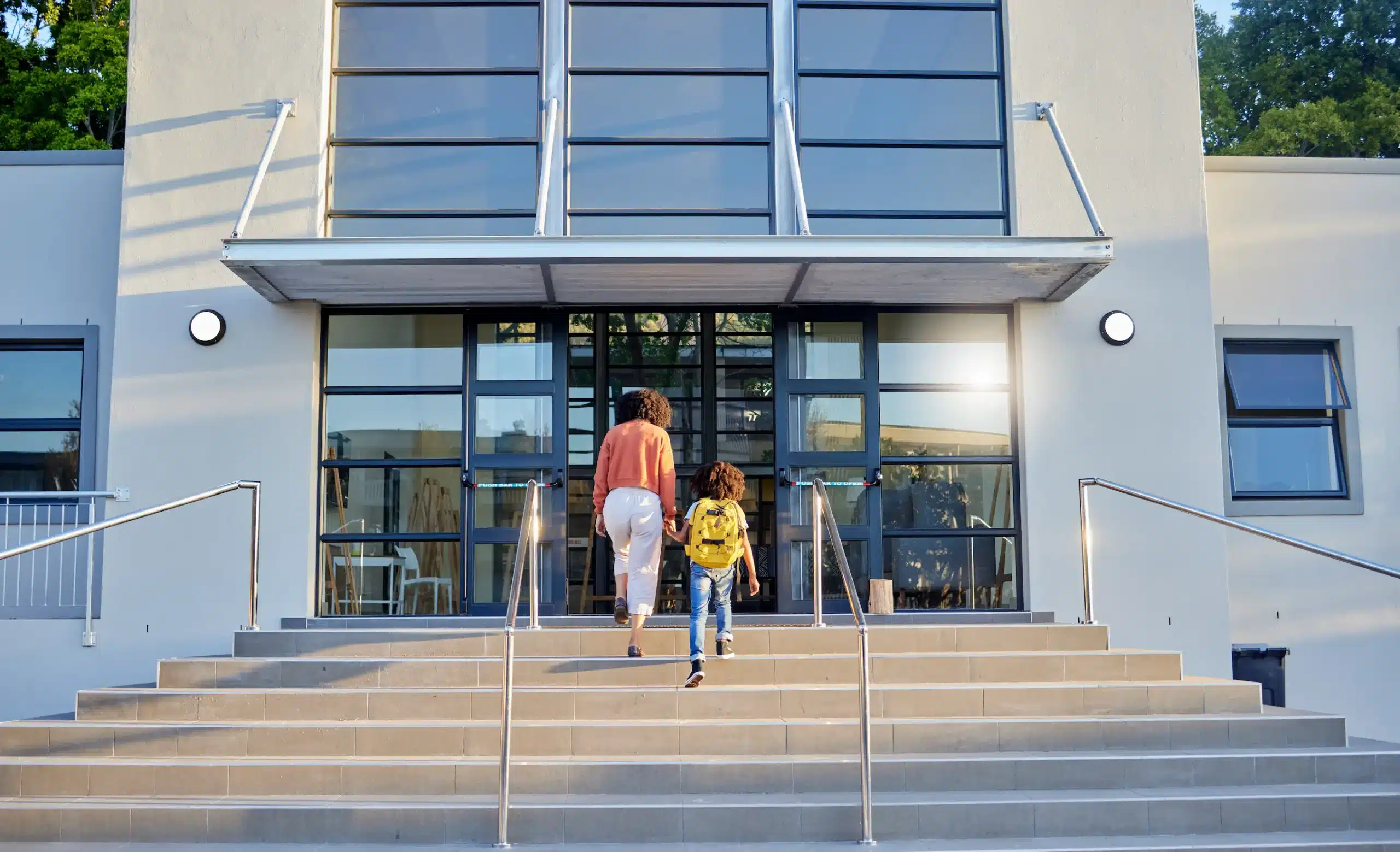 A woman and child ascend the stairs leading to a school entrance