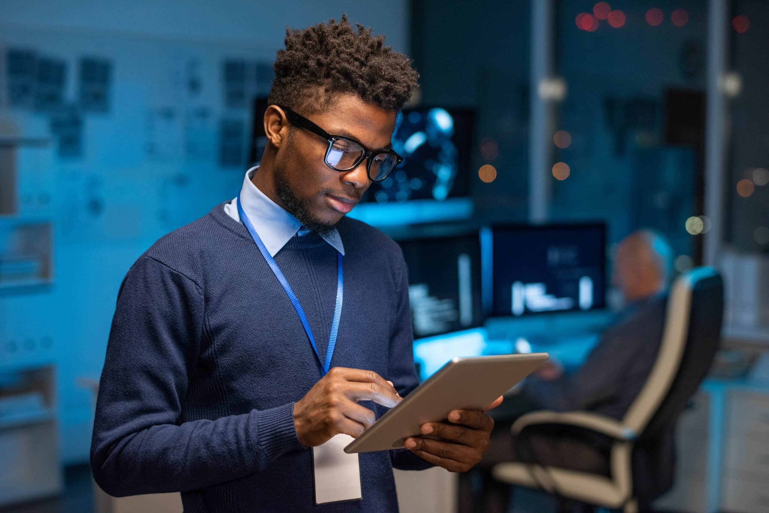 A man wearing glasses is focused on using a tablet computer.