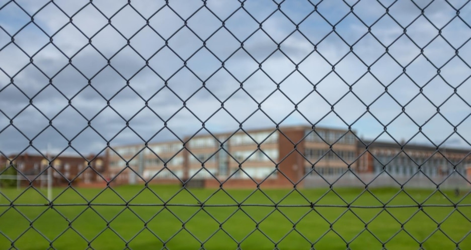 Exterior of a school seen through a chain link fence