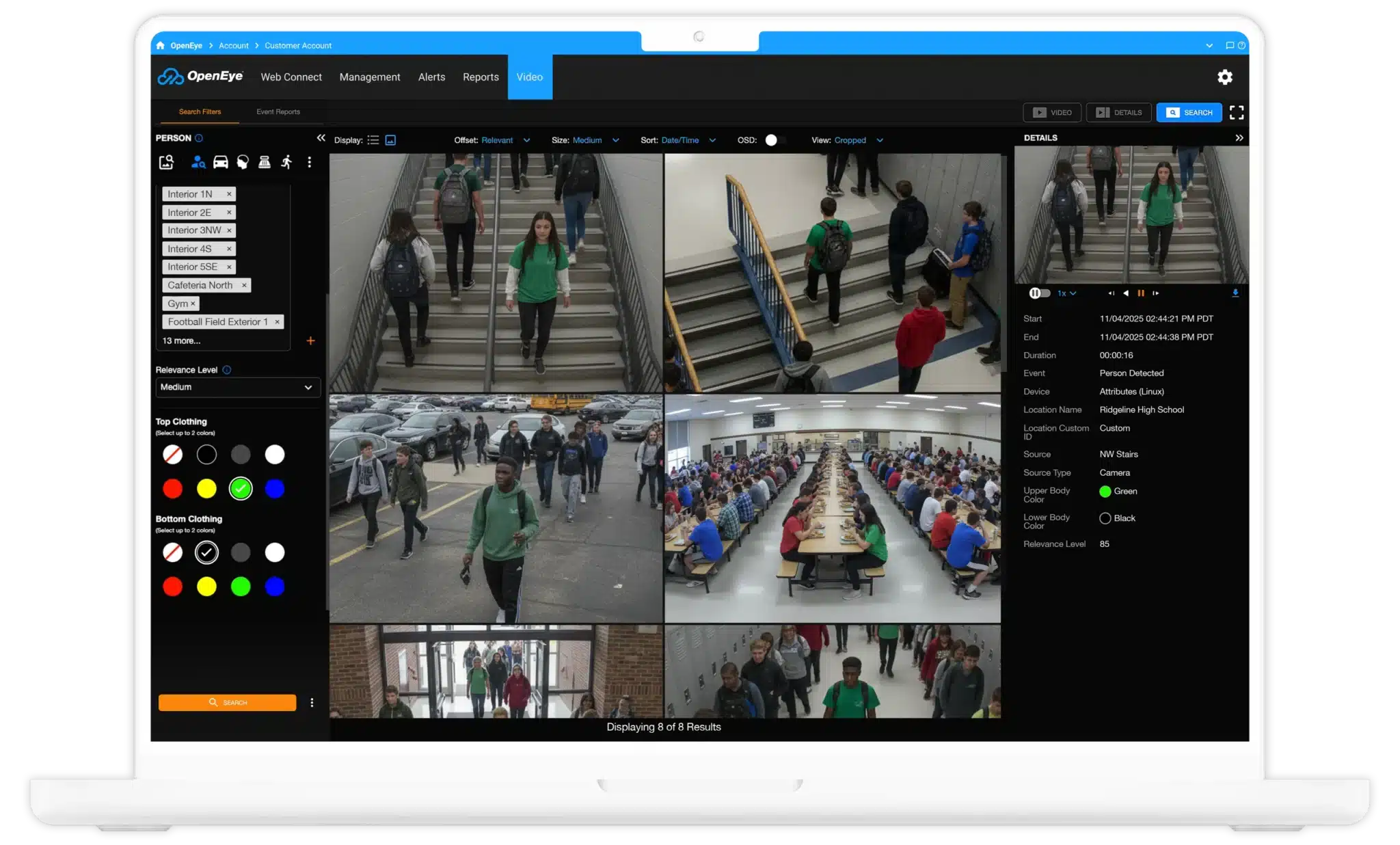 A laptop displays OpenEye Web Services, showing security footage of students in green clothing walking in a school hallway.