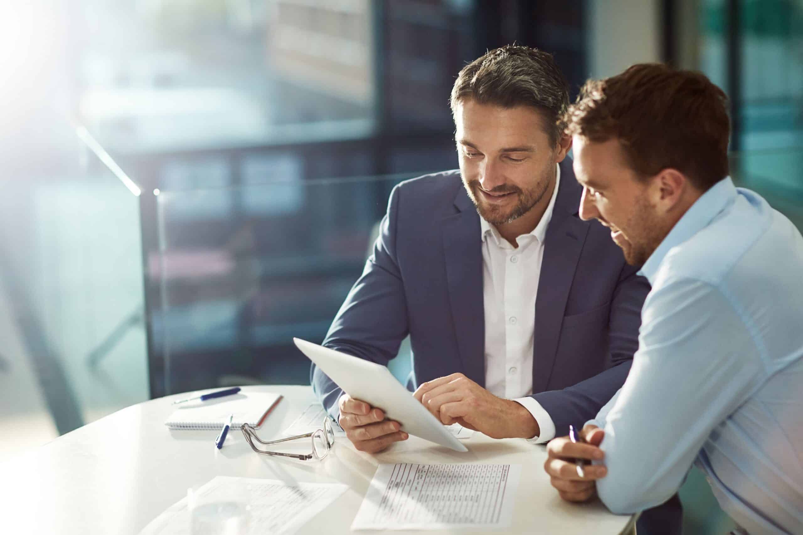 Two business men seated at a table, focused on financial documents in front of them
