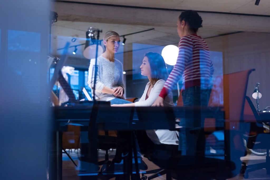 Three women are gathered at a table in an office