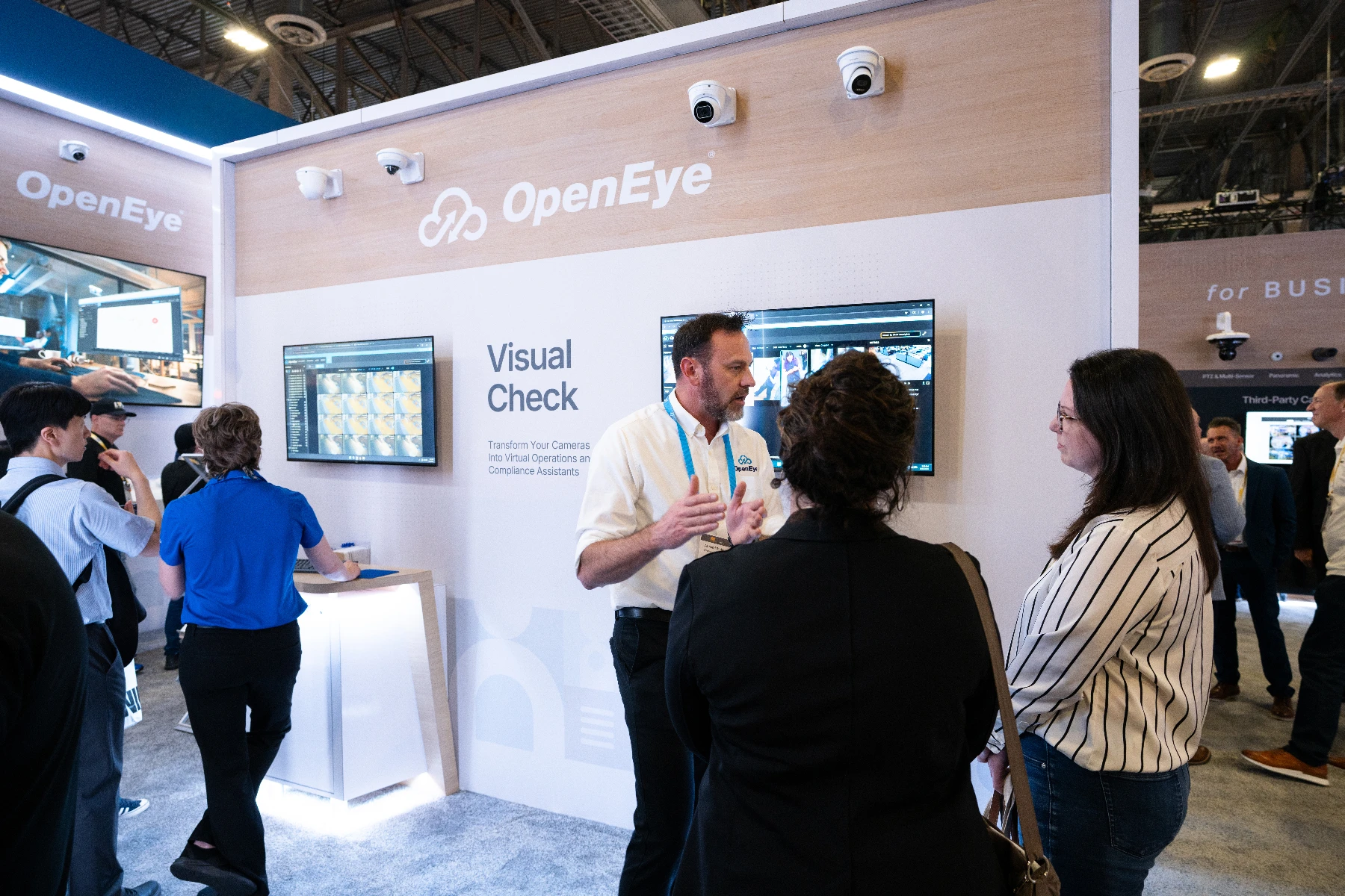 An OpenEye employee gives a demo to two people in a trade show booth