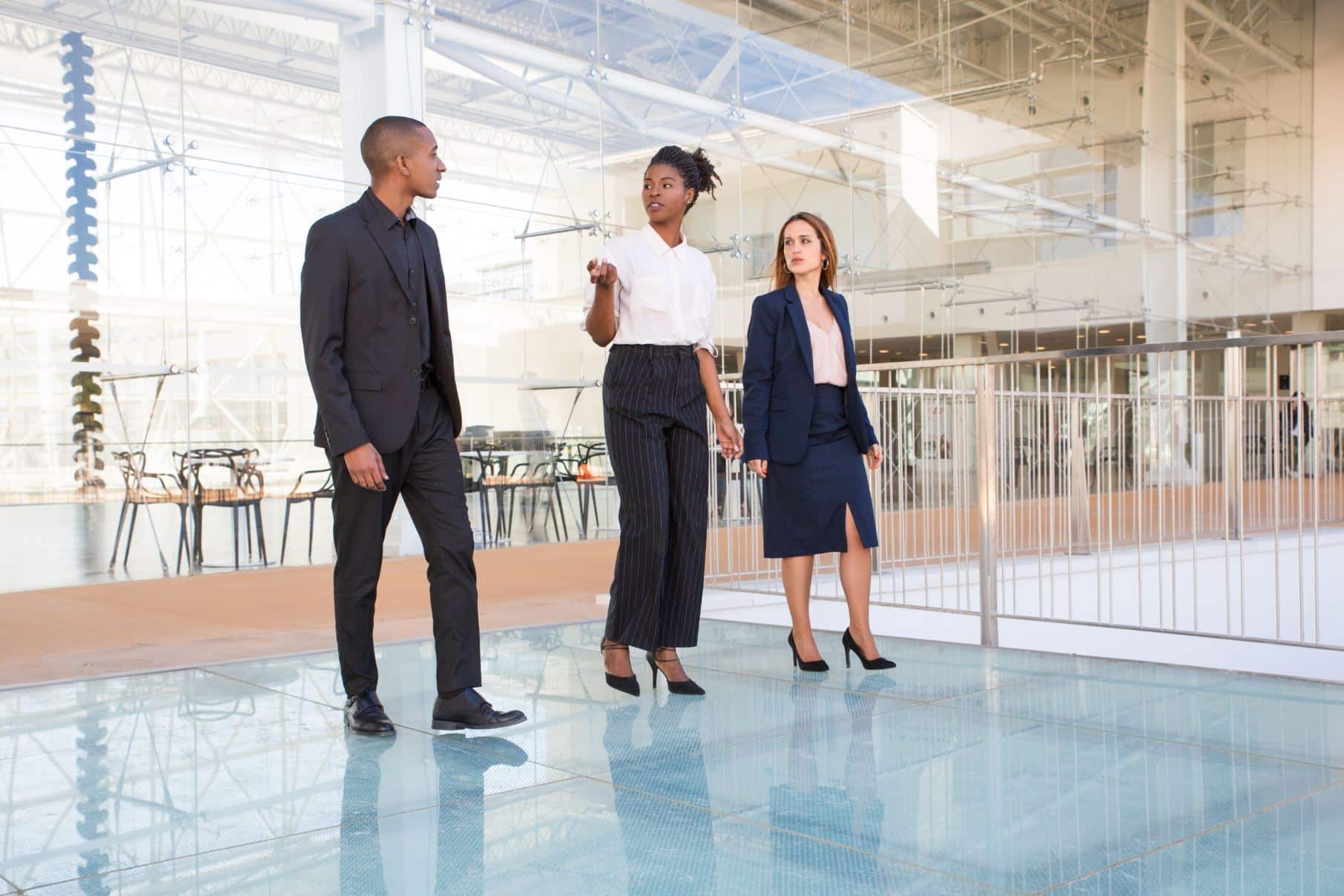 Three business professionals walk through a modern commercial building, engaged in conversation.