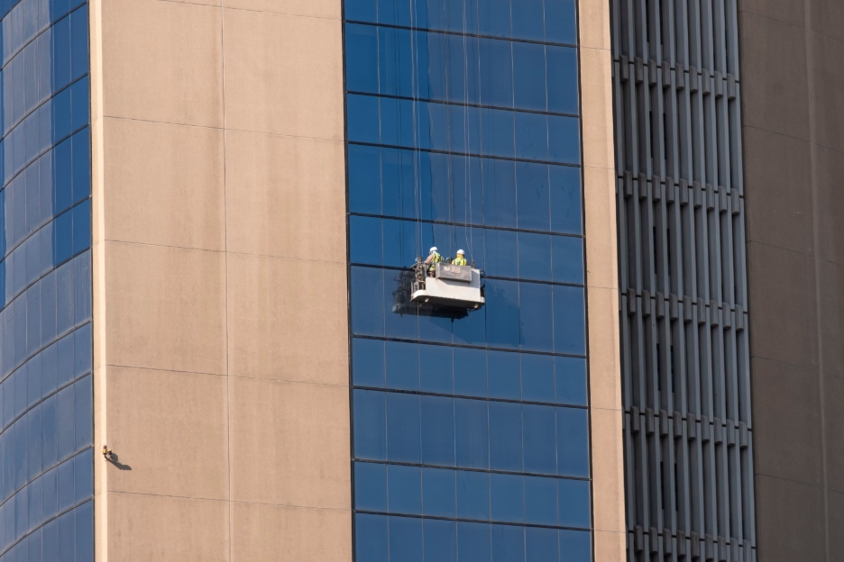 Window cleaners work on the side of a tall building.