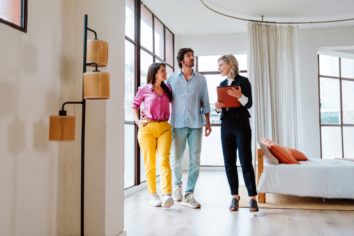 Man and woman being led on a tour by a real estate agent in a multi-family real estate setting.