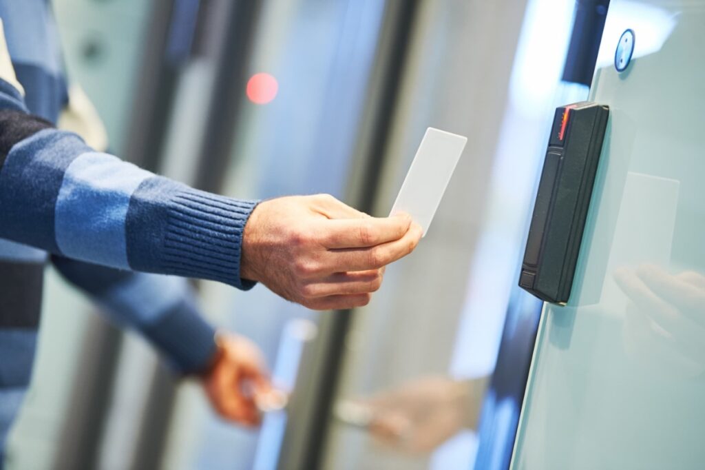 Key card held to door access control system by arm in blue striped sweater.