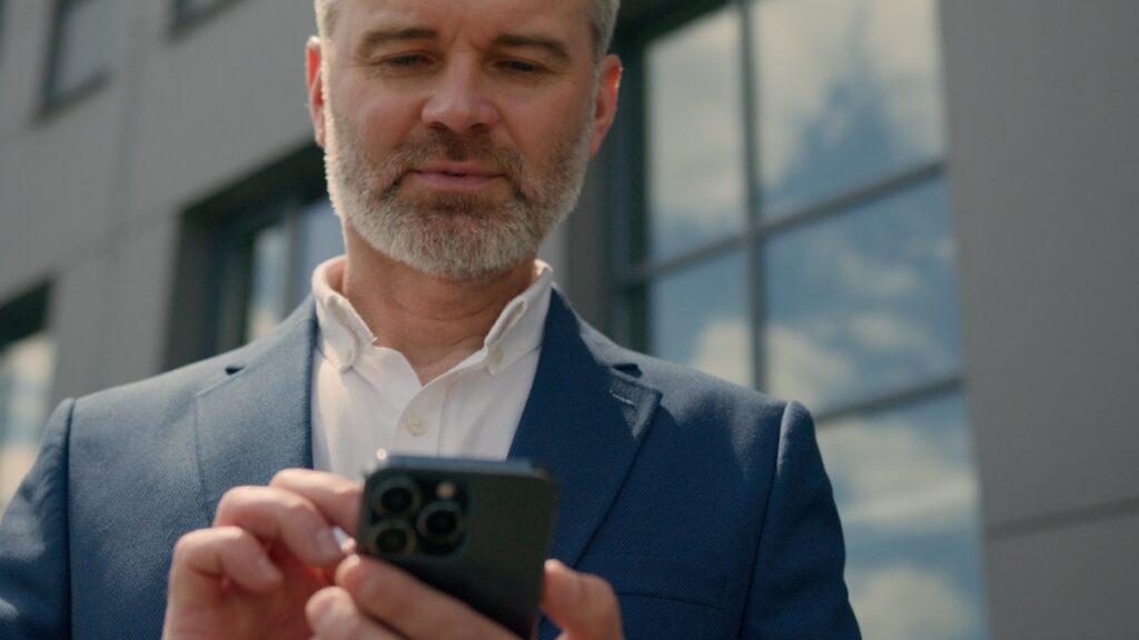Man in suit staring down at phone screen.