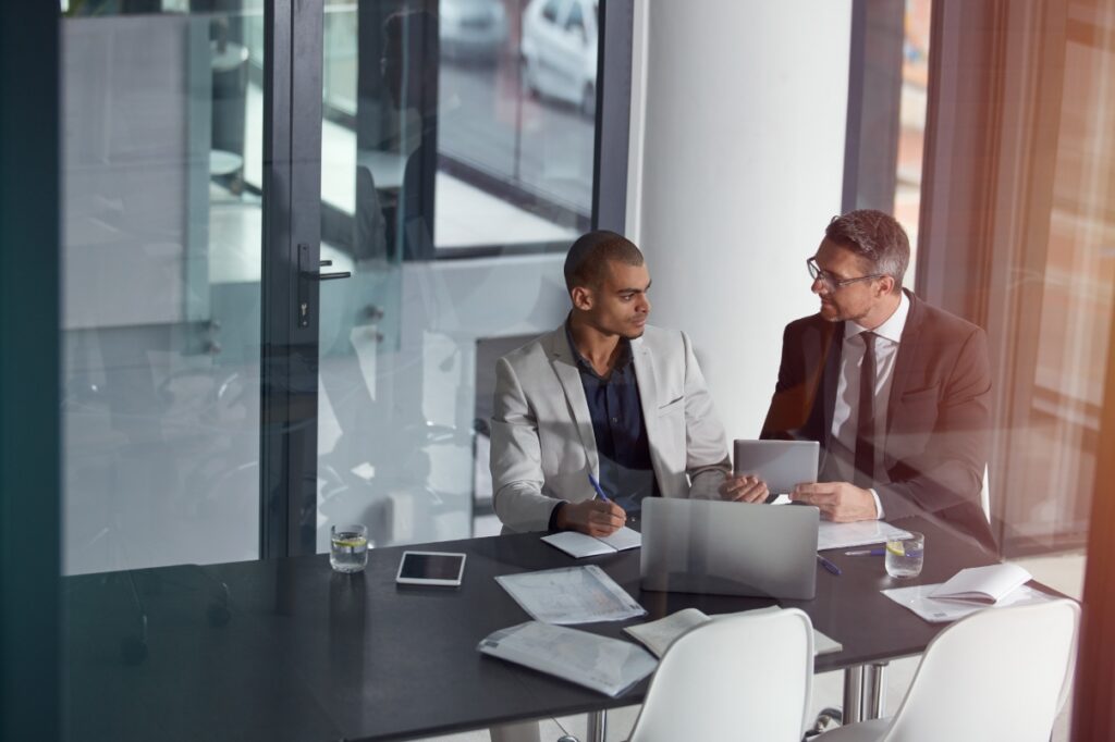 Two men sit in an office conference room.