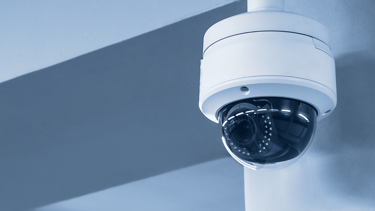 Dome video surveillance camera attached to wall.
