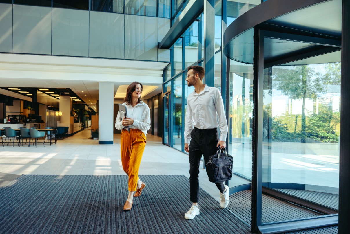A woman and man walk side by side in a modern commercial building.