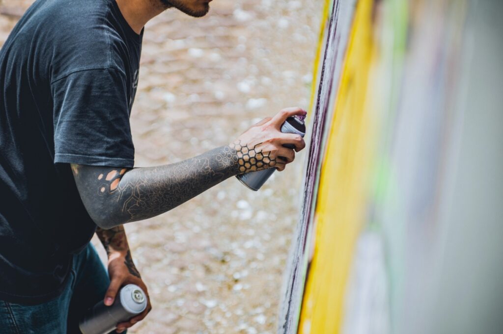 An individual spray paints a wall.