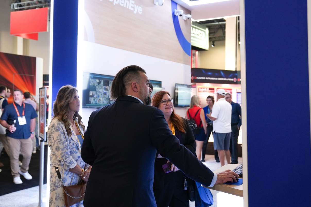 An OpenEye employee demonstrates OpenEye Web Services to two people at a video security trade show.
