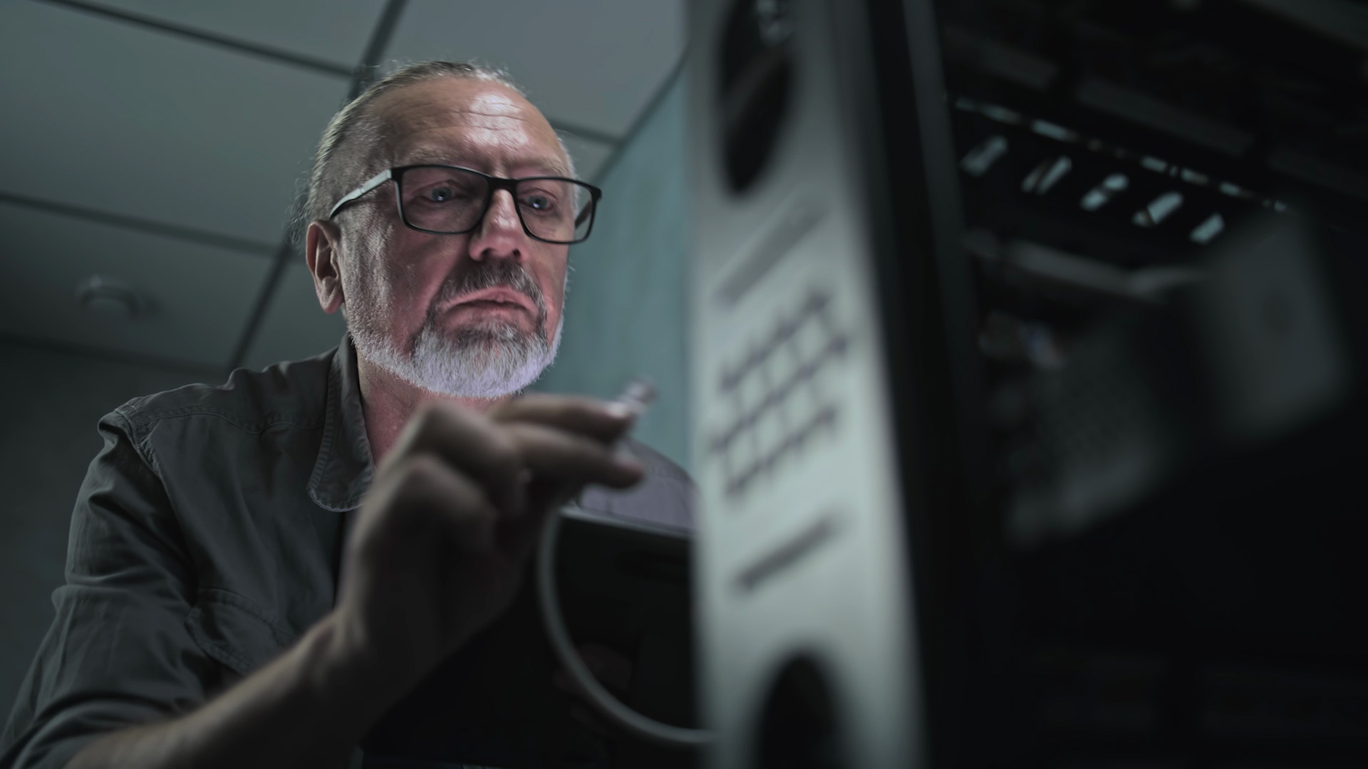 A man holds a wire next to a server.