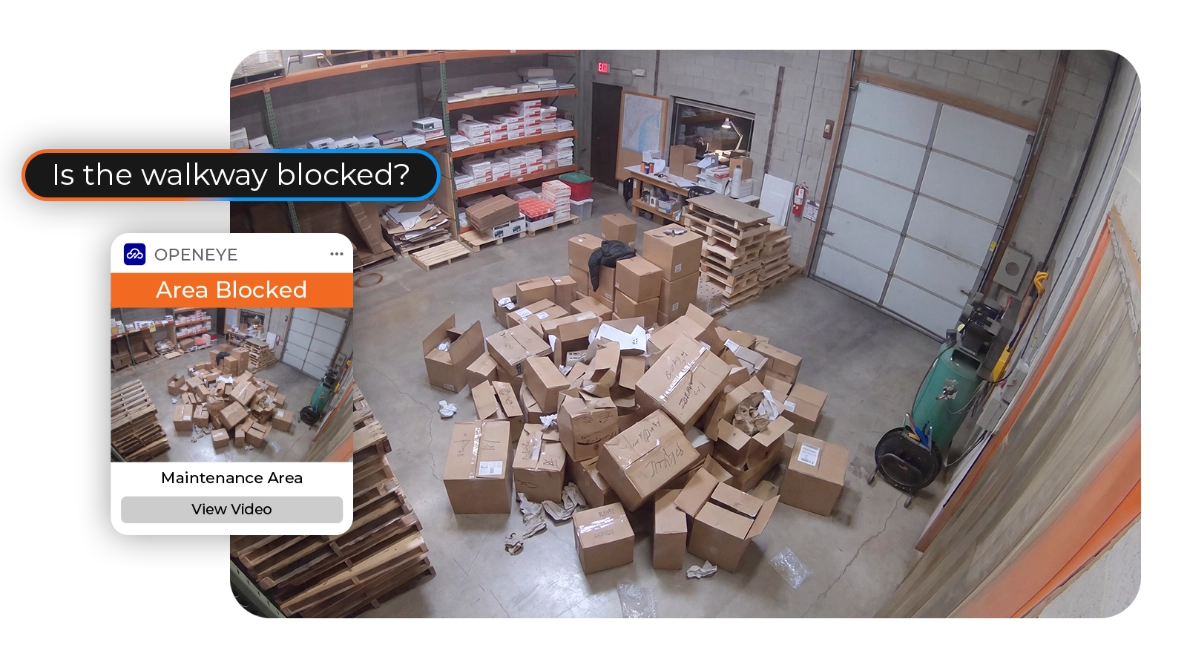 A warehouse scene depicts a pile of boxes blocking the center of a room, with a prompting screen and alert on the left side of the scene reading, "Is the walkway blocked? OPENEYE. Area Blocked. Maintenance Area. View Video."