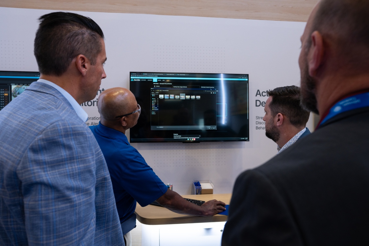 An OpenEye employee demonstrates OpenEye Web Services to three individuals at a physical security trade show.