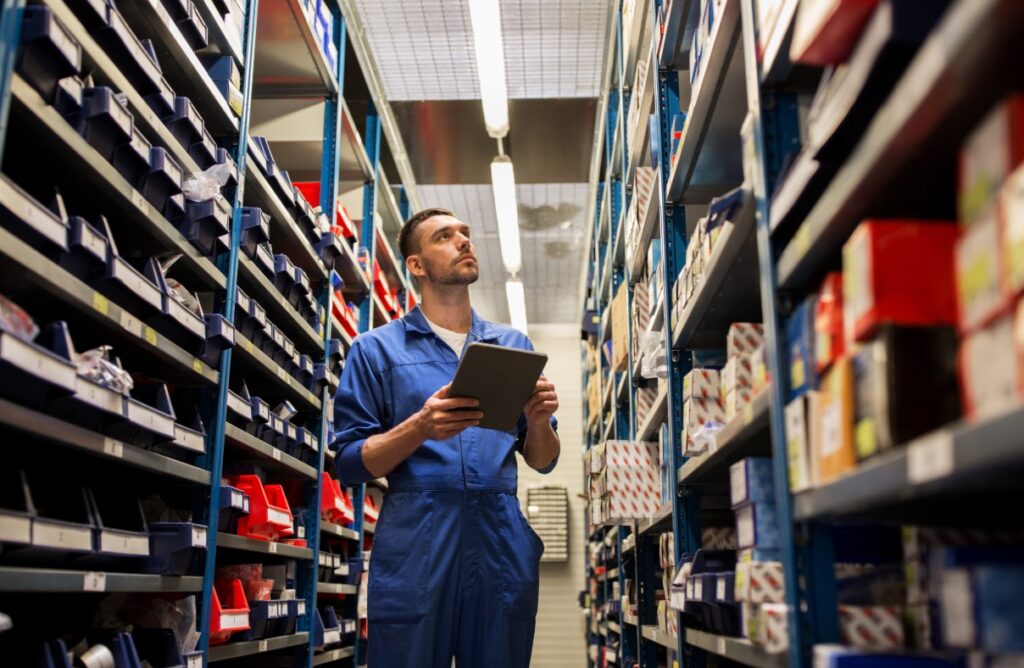 An auto parts retail employee checks inventory within a store.