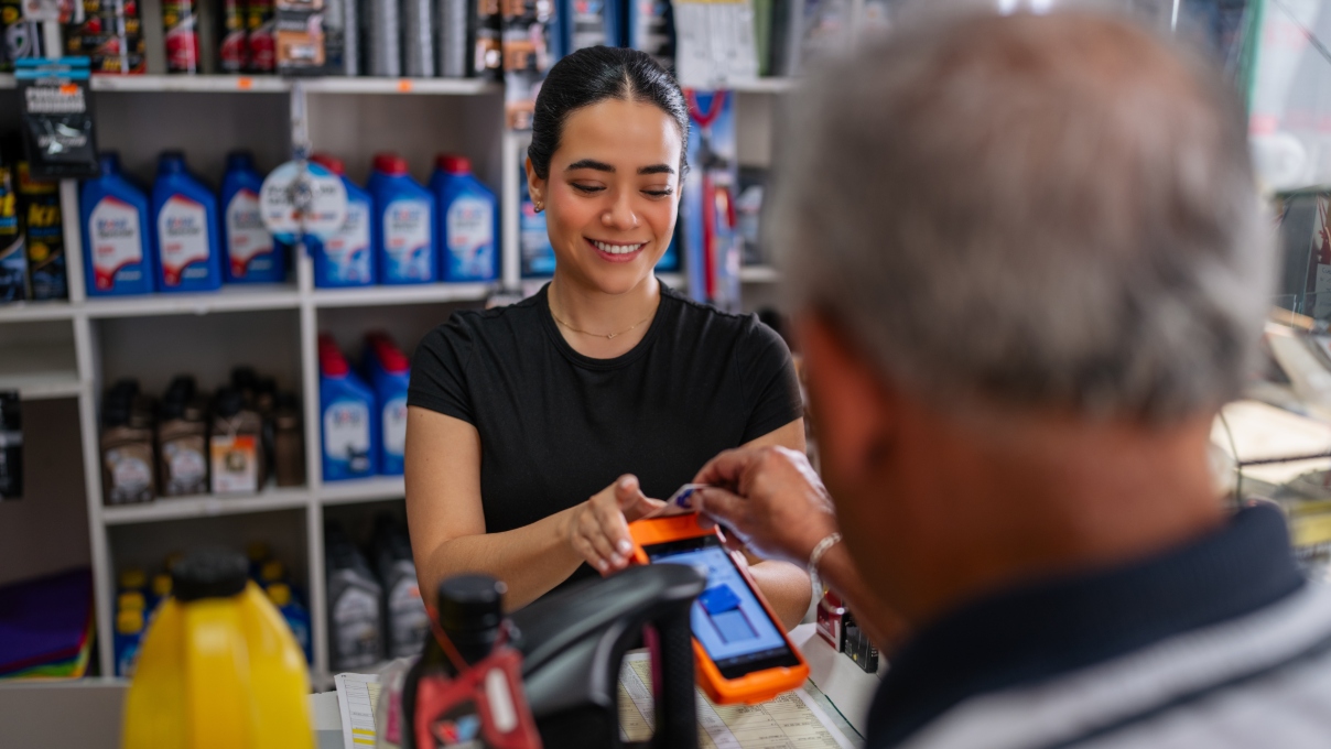 An employee helps a customer check out at a retail automotive parts store.