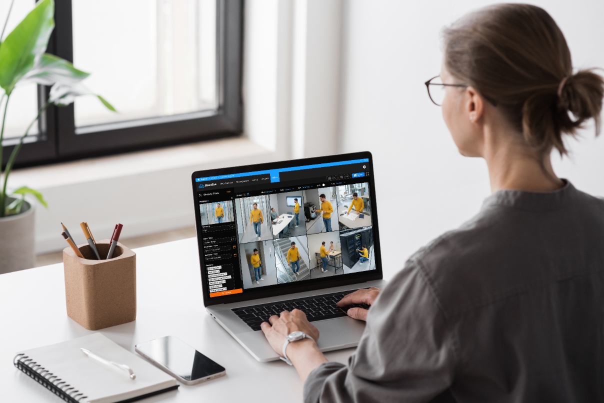 A woman in an office setting uses OpenEye Web Services's AI-powered Similarity Search to find security video clips of a specific individual.